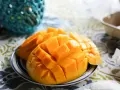 En skål med skivad mango, full av vitaminer, på en duk med mönster.
