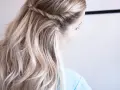 En kvinna med vackert, halvt uppsatt hår med en flätad detalj. Håret är blont och vågigt.