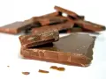 En hög med chokladbitar, några staplade, andra utspridda. Chokladfinnarna ser sega och söta ut.