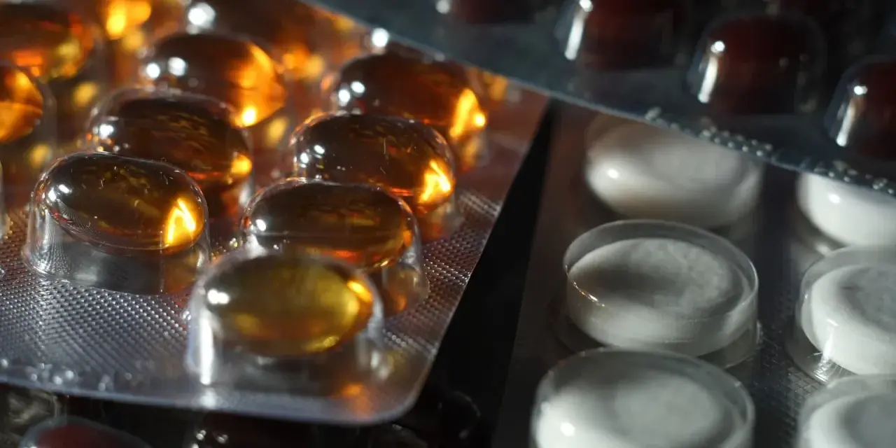 Närbild på flera blisterförpackningar med piller. En förpackning innehåller gulaktiga kapslar, en annan vita tabletter och en tredje mörkbruna piller. Kanske en av dem innehåller folic acid svenska.