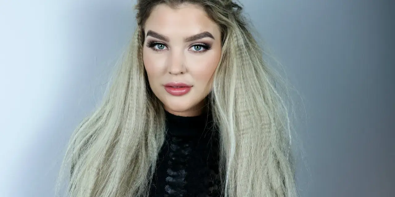 En kvinna med blå ögon och en snygg makeup har sitt blonda hår stylat med en våffla.
