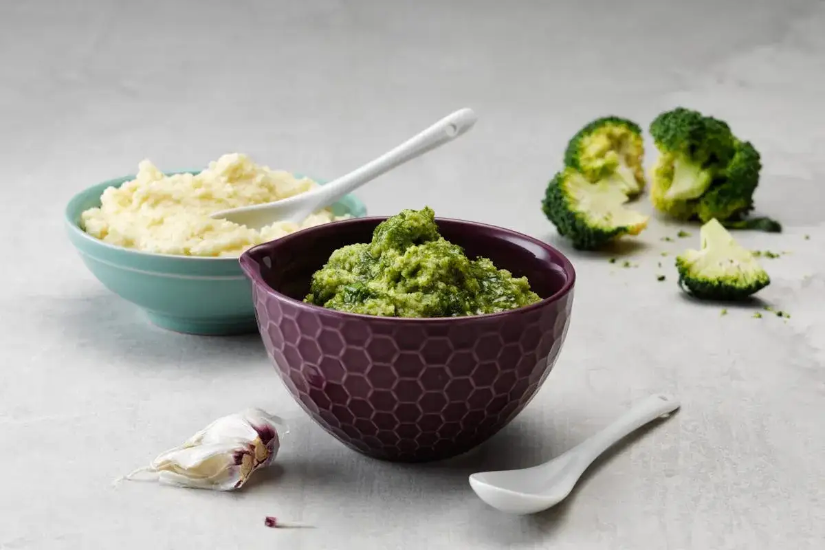 Gr&ouml;n broccoli-r&ouml;ra i sk&aring;l, bredvid en sk&aring;l med ljus pur&eacute;. Broccoli &auml;r full av vitaminer.
